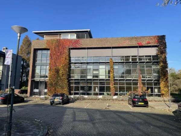 Kantoorgebouw aan de Jan Leentvaarlaan met grote ramen, begroeid met herfstkleurige klimop.